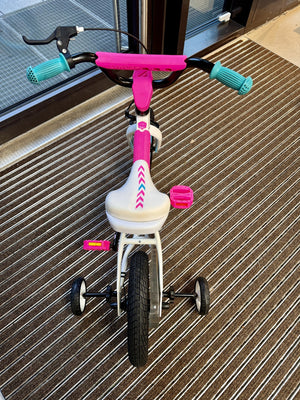 Toppsikt av hvit og rosa Mechanic Arts Snurr balanse sykkel – detalj av styre, sete og pedaler på barnesykkel
