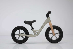 Beige Mechanic Arts Trillr balanse sykkel på hvit bakgrunn, studiofoto fra siden – enkel og elegant barnesykkel uten pedaler